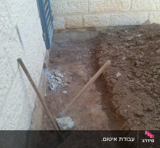 כלים לחפירה ואיטום ליד קיר אבן